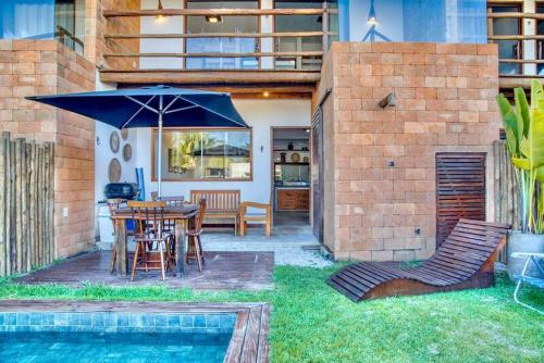 a patio with a table and chairs and an umbrella at Casa piscina privativa e vista-mar - Milagres in Passo de Camarajibe