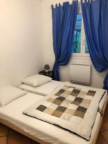 - une chambre avec 2 lits avec des rideaux bleus et une fenêtre dans l'établissement Gite de font du roux, à Flayosc