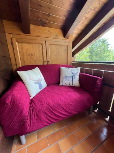 a purple couch sitting in a room with a window at Appartamento Diamante - Ad un passo dalla Ciclabile in Auronzo di Cadore