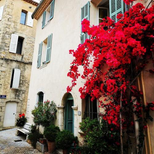 un bâtiment avec des fleurs rouges sur son côté dans l'établissement Azur et vous en provence, à Laouque