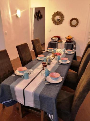 une grande table avec des chaises, des assiettes et de la vaisselle dans l'établissement Azur et vous en provence, à Laouque