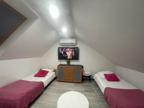 a attic room with two beds and a tv at APARTAMENT KRÓLEWSKI CENTRUM NIEPOŁOMICE in Niepołomice