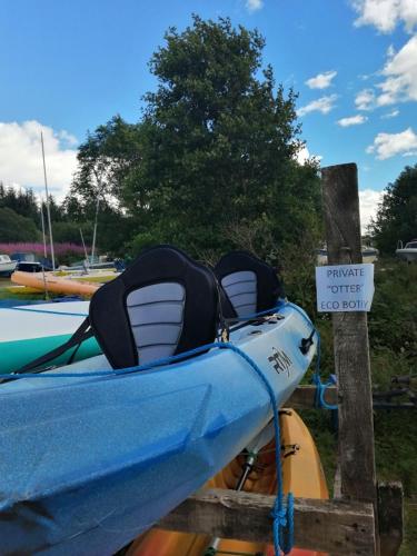 a boat tied up to a dock with a sign at Otter - Eco Bothy with Hot Tub in Castle Douglas