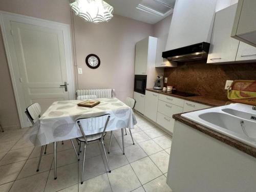 a kitchen with a table with chairs and a clock on the wall at Les tilleuls in Soustons