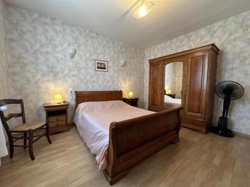 a bedroom with a bed and a chair and a mirror at Les tilleuls in Soustons