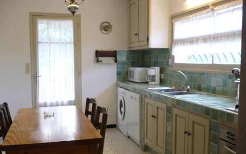 La cuisine est équipée d'une table, d'un évier et d'un lave-vaisselle. dans l'établissement Villa l'abri cotier, à Sainte-Maxime