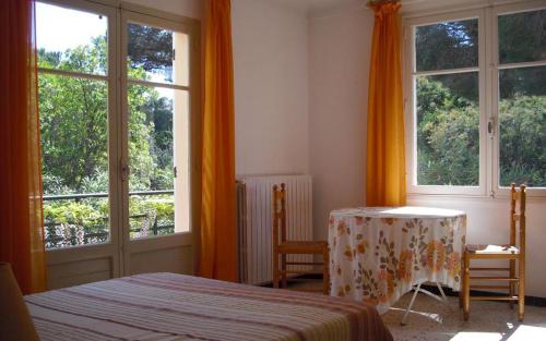 une chambre avec un lit, une table et des fenêtres dans l'établissement Villa l'abri cotier, à Sainte-Maxime