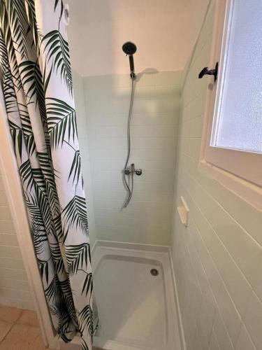 La salle de bains est pourvue d'une douche avec un rideau de douche noir et blanc. dans l'établissement Gite 625 avec piscine, à Sainte-Maxime