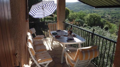 a table and chairs on a balcony with an umbrella at Le font castellan in Bauduen