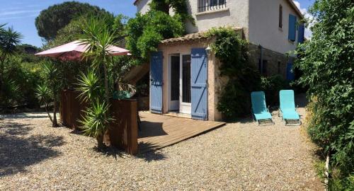 een huis met twee blauwe stoelen en een veranda met een parasol bij Gite 525 avec piscine in Sainte-Maxime