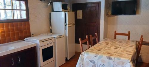 une cuisine avec une table et un réfrigérateur blanc dans l'établissement Le gite delfino, à Trigance