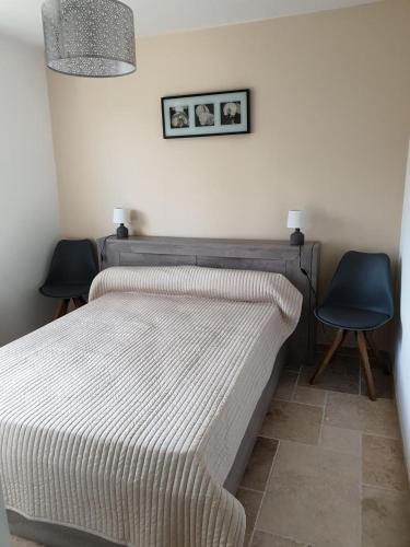 - une chambre dotée d'un lit avec 2 chaises et d'une photo sur le mur dans l'établissement L'amandier, à Moissac-Bellevue