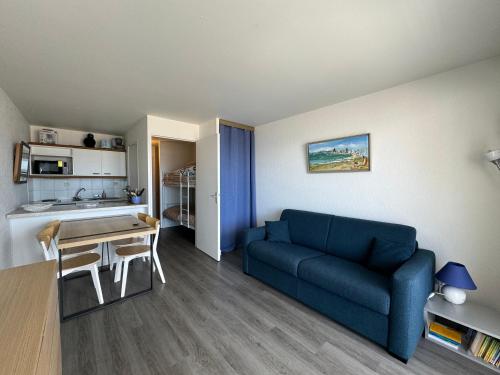 a living room with a blue couch and a table at Cocon côtier - Vue sur Mer - Parking - Proche de la Thalasso - Terrasse in Pornichet