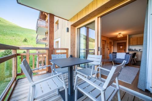 a dining room with a table and chairs on a deck at Residence Hameau de Clotaire Alpe d'Huez - by EMERALD STAY in L'Alpe-d'Huez