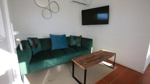 a living room with a green couch and a table at Bella Vista Hôtel, Suites & Maisons in Porticcio