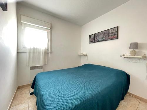 une chambre avec un lit bleu et une fenêtre dans l'établissement Charmant 2 pièces à Sète, à 300m de la plage avec parking et loggia vitrée - FR-1-338-302, à Sète