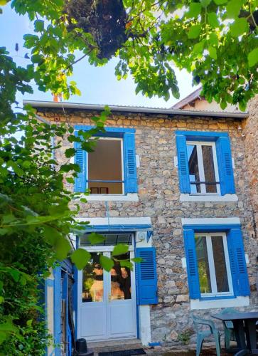 une maison en pierre avec volets bleus dans un bâtiment dans l'établissement Maison Centre Village, à Craponne-sur-Arzon
