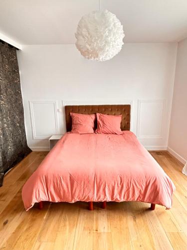 - une chambre avec un lit doté d'oreillers roses et d'un lustre dans l'établissement Maison moderne et lumineuse, à Chennevières-sur-Marne