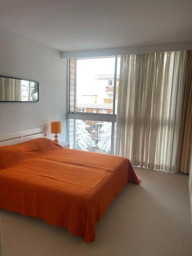- une chambre avec un lit orange et une grande fenêtre dans l'établissement Vallonpierre, à Orcières