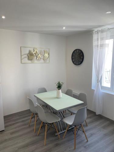 une salle à manger avec une table, des chaises et une horloge dans l'établissement Charmant Appart clim 6 pers, Sorgues Vaucluse 1, à Sorgues