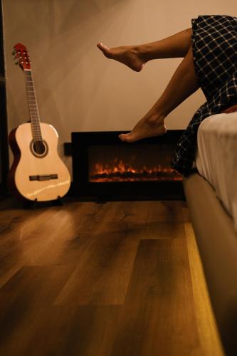 a woman sitting in front of a fireplace with a guitar at Primo Cabana - Hospedagem na Vinícola in Quatro Barras