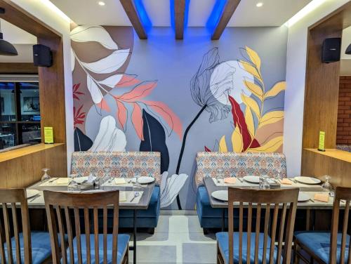 a dining room with tables and chairs and a mural at Hotel Red Chillee Restro in Silvassa