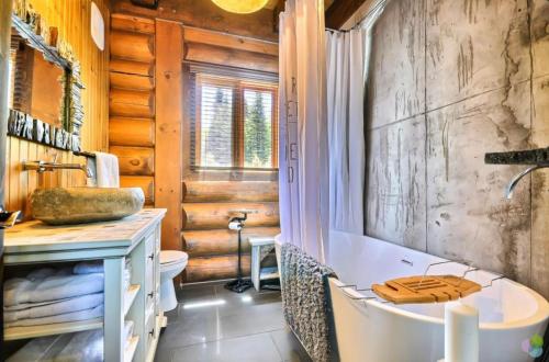 ein Badezimmer mit Badewanne, Toilette und Waschbecken in der Unterkunft Peaceful Log-Style Chalet with hot tub in Lac-Superieur
