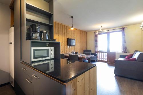 a living room with a kitchen with a microwave at Résidence Les Balcons de Val Thorens & Spa in Val Thorens