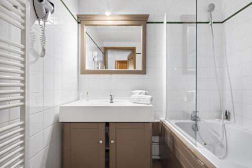 a bathroom with a sink and a mirror and a tub at Résidence Les Balcons de Val Thorens & Spa in Val Thorens