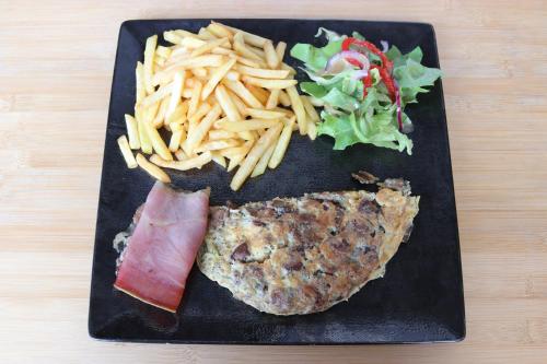 a black plate of food with a steak and a salad at Hotel Mendy in Saint-Jean-le-Vieux