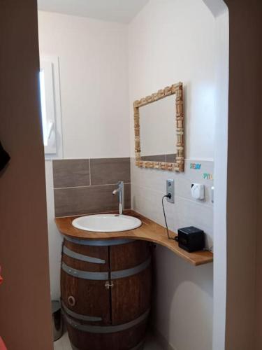 une salle de bain avec un lavabo et un miroir sur un tonneau dans l'établissement Maison 120 m2, piscine chauffée, en bordure de forêt, à Mios