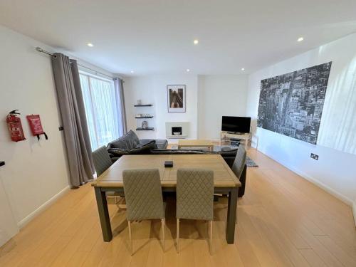 een woonkamer met een houten tafel en stoelen bij Parc y Bryn Serviced Apartments in Aberystwyth