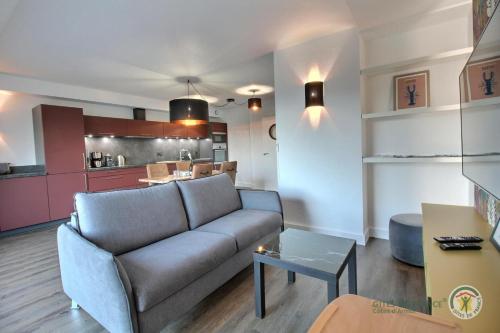 un salon avec un canapé et une cuisine dans l'établissement La terrasse sur le golf, à Pleumeur-Bodou