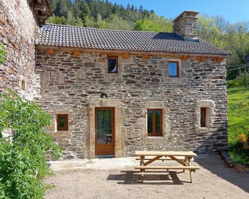 a stone house with a picnic table in front of it at Gite de montredon in Cubières