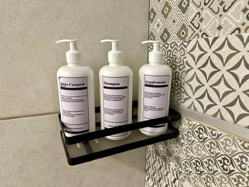 a group of three shampoo bottles on a shelf in a bathroom at Quark Apartments in Lima