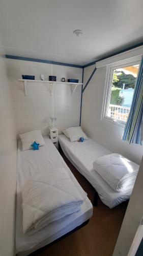 two twin beds in a room with a window at Bungalow bord de mer in Les Mathes