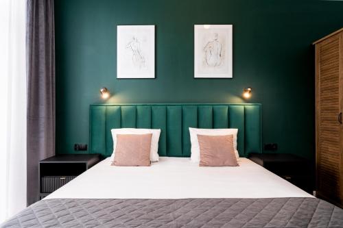 łóżko z zielonym zagłówkiem i 2 różowymi poduszkami w obiekcie Wawel Boutique Residence - Krakow Old Town w Krakowie