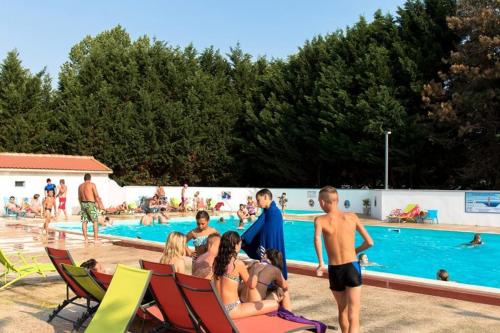 un groupe de personnes assises autour d'une piscine dans l'établissement Bungalow bord de mer, aux Mathes