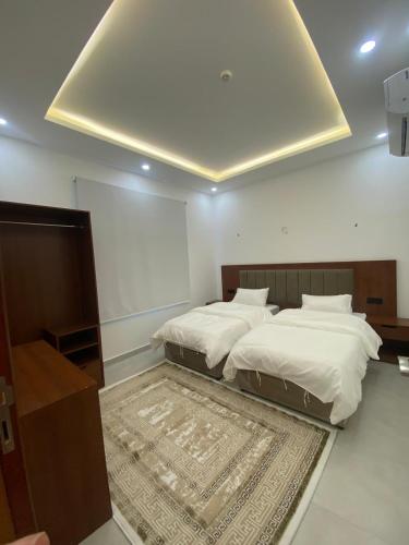 a bedroom with two twin beds and a rug at قصر أباهي للوحدات السكنية المفروشة in Al Nairyah