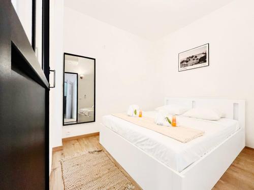 - une chambre blanche avec 2 lits et un miroir dans l'établissement L’Iris - Suquet Cannes Centre, à Cannes