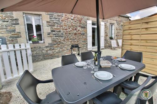 une table noire avec des chaises et un parasol dans l'établissement Ker'luane, à Lézardrieux