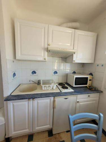 une cuisine avec des armoires blanches, un évier et un micro-ondes dans l'établissement 616 - joelle pagano, à Palavas-les-Flots