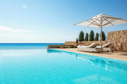 a swimming pool with two lounge chairs and an umbrella at Sani Club in Sani Beach