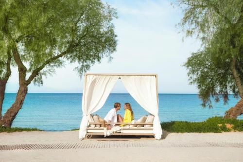 two people sitting on a bed on the beach at Sani Club in Sani Beach