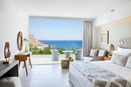 a bedroom with a bed and a large window at Ikos Aria in Kefalos