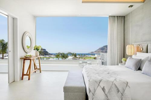 a bedroom with a large bed and a large window at Ikos Aria in Kefalos
