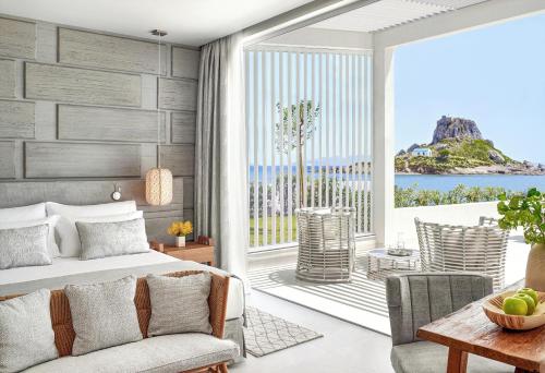 a bedroom with a bed and a view of the ocean at Ikos Aria in Kefalos