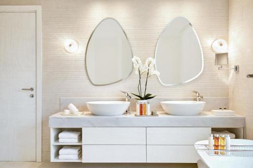 a bathroom with two sinks and two mirrors at Ikos Aria in Kefalos