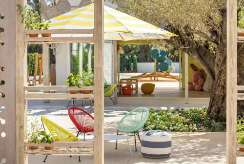a patio with colorful chairs and an umbrella at Ikos Andalusia in Estepona