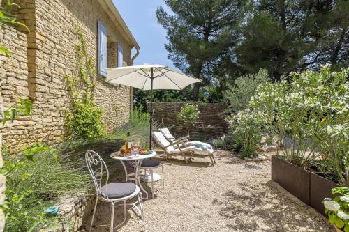a patio with a table and chairs and an umbrella at Le Mas de Caroline in Gargas